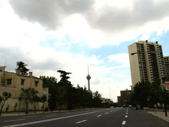 Road by buildings against sky