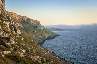 Scenic view of sea by mountains against clear sky