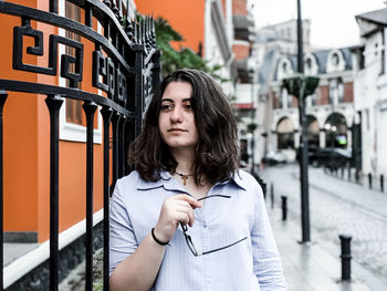 Beautiful woman standing by gate in city