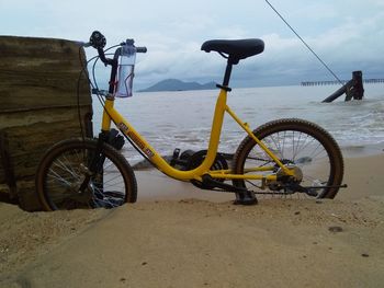 Bicycle by sea against sky