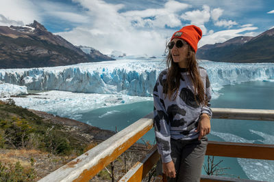 Portrait of young woman standing against snowcapped mountains