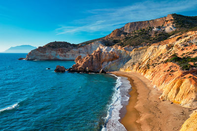 Scenic view of sea and mountains against blue sky