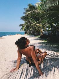 Rear view of woman sitting on beach