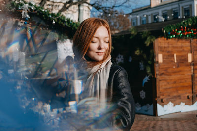 Young redhead woman enjoying the sun and drinking take away coffee wandering on winter city streets