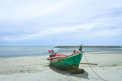 Fishing boat on beach against sky