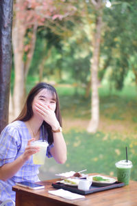 Young woman using mobile phone while sitting at park