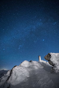 Low angle view of snow covered mountains against sky at night