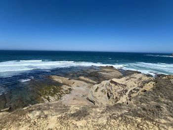 Scenic view of beach against clear blue sky