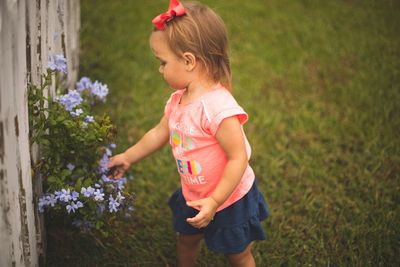 Baby girl touching flowers in yard