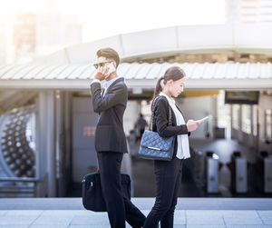 Side view of colleagues using phones elevated walkway