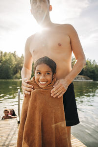 Smiling girl wrapped in towel while standing with father