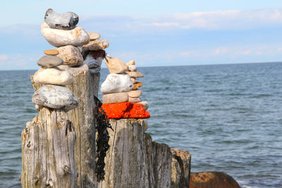 Stack of wooden post in sea against sky