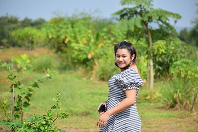 Portrait of smiling young woman standing on field