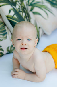 Portrait of cute baby boy lying on bed at home