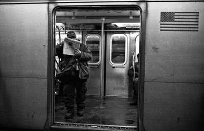 Man reading newspaper while standing in train