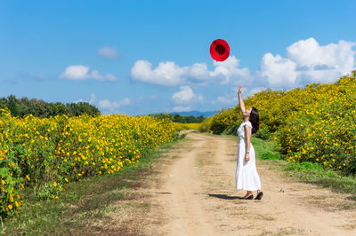 Woman standing on land by road against sky