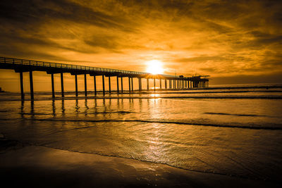 Pier on beach during sunset