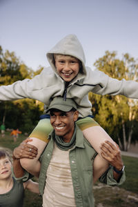 Male camp counselor carrying boy on shoulders while having fun in playground