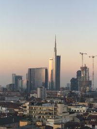 Modern buildings in city against clear sky during sunset