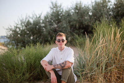 Portrait of young man sitting on field