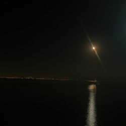 Illuminated sea against clear sky at night