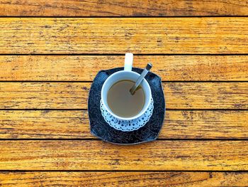 Cup of tea on a plate placed on a rustic wooden table
