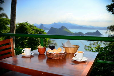 Coffee cup on table against mountains and sky