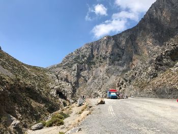 Vehicles on road by mountain against sky