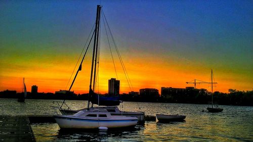 Sailboats in sea at sunset