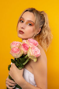 Portrait of a beautiful young woman holding yellow flower