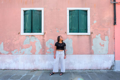 Full length portrait of woman standing against building