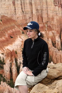 Man looking away while sitting on rock