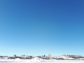 Buildings in city against clear blue sky