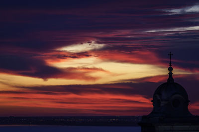 Silhouette of statue against cloudy sky during sunset