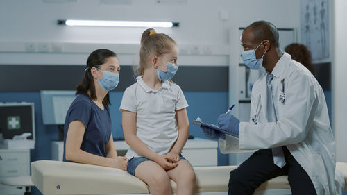 Doctor wearing mask examining girl in hospital