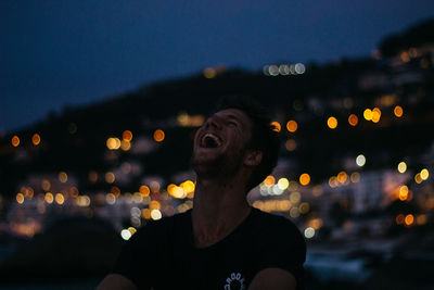 Portrait of young man looking away in city at night