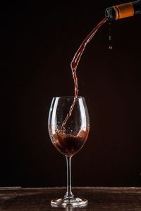 Close-up of wineglass on table against black background