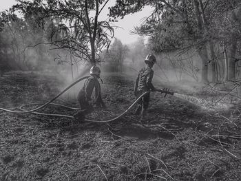 Firefighter spraying water on field with fire hose