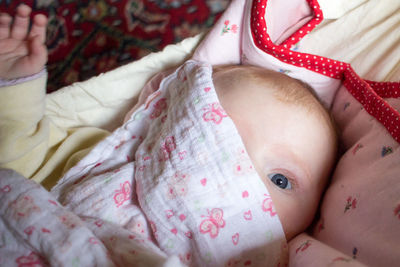 Close-up portrait of cute baby girl lying on bed