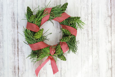 Directly above shot of pinewreath with pinecones and red white checked ribbon on table ,diy