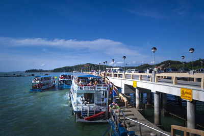 Boats moored in sea against blue sky