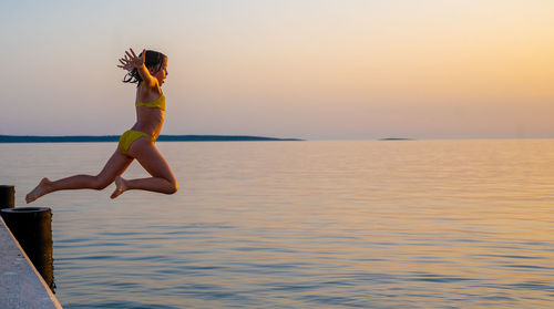 Rear view of woman jumping in sea