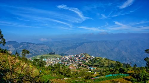 Aerial view of townscape and mountains against blue sky