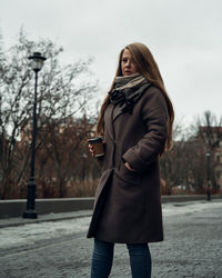 Full length of woman standing on mobile phone in winter