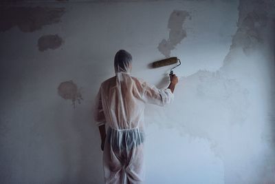 Rear view of woman standing against wall