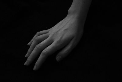 Cropped hand of woman over black background