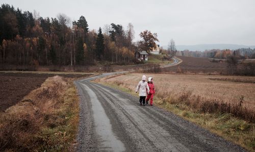 Rear view of people walking on road against sky