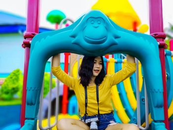 Smiling woman looking away while sitting in playground