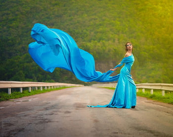 Woman with blue umbrella standing on grassland