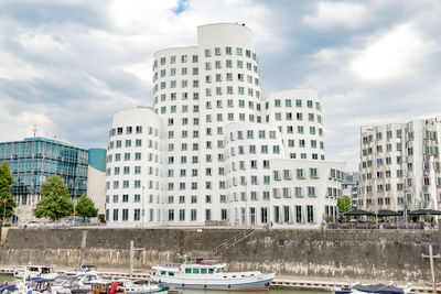 Buildings by river against sky in city